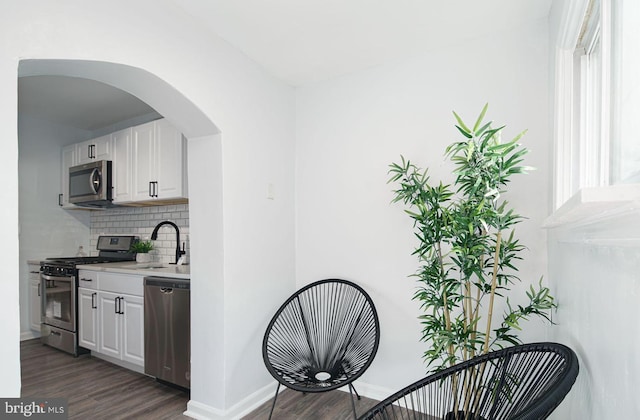 interior space with stainless steel appliances, dark hardwood / wood-style floors, sink, white cabinetry, and backsplash