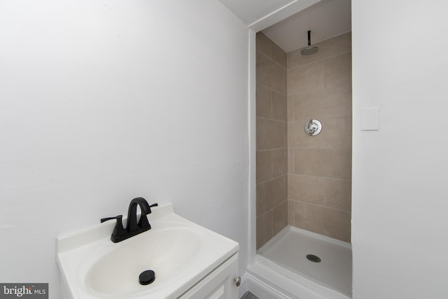 bathroom with a tile shower and vanity