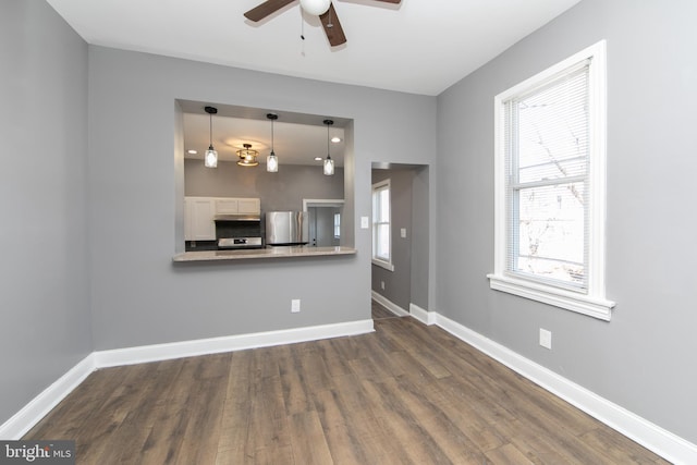 unfurnished living room featuring ceiling fan, dark wood-type flooring, and a wealth of natural light