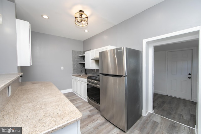 kitchen featuring light hardwood / wood-style flooring, stainless steel appliances, white cabinetry, and tasteful backsplash