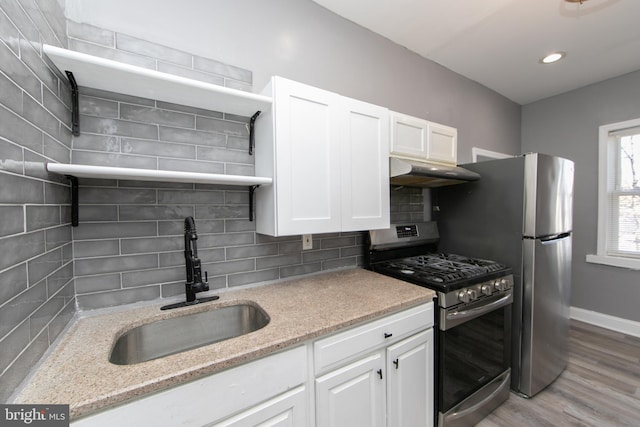 kitchen featuring stainless steel appliances, sink, white cabinets, light stone counters, and tasteful backsplash