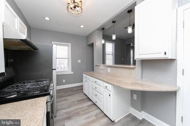 kitchen with stainless steel gas stove, decorative backsplash, white cabinetry, and wall chimney exhaust hood