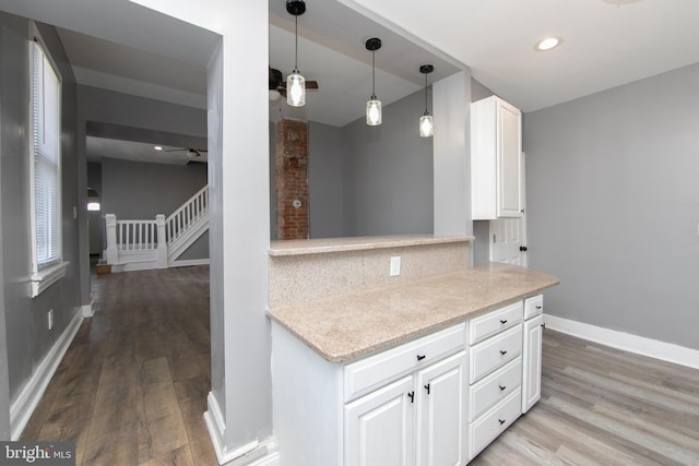 kitchen featuring white cabinetry, light wood-type flooring, ceiling fan, and light stone counters