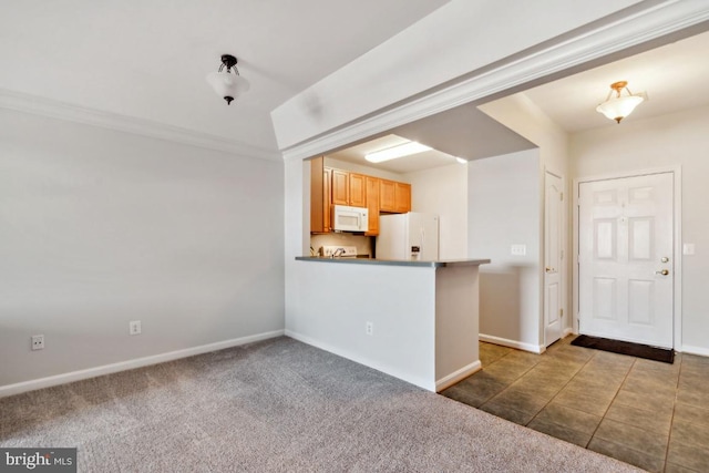 kitchen featuring white appliances, ornamental molding, kitchen peninsula, and dark colored carpet