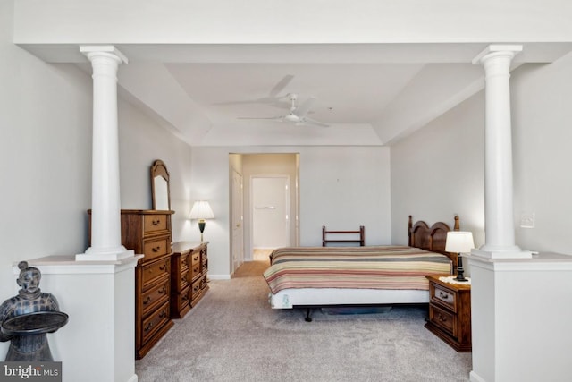 carpeted bedroom featuring ceiling fan, a tray ceiling, and ornate columns