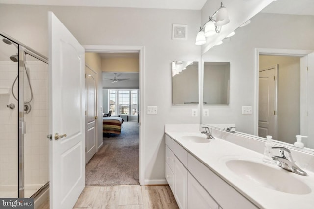 bathroom featuring a shower with door and vanity