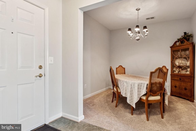 carpeted dining room with a chandelier