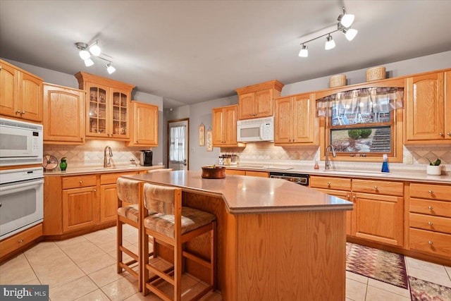 kitchen featuring a kitchen island, backsplash, white appliances, and a breakfast bar area