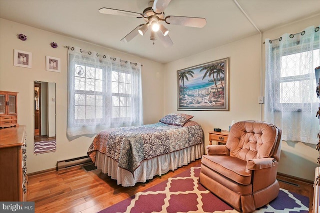 bedroom featuring multiple windows, a baseboard radiator, ceiling fan, and light wood-type flooring