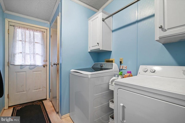 washroom featuring washing machine and clothes dryer, ornamental molding, a textured ceiling, and cabinets