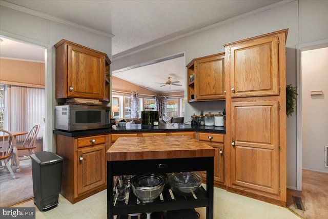 kitchen with vaulted ceiling, wood counters, crown molding, kitchen peninsula, and ceiling fan