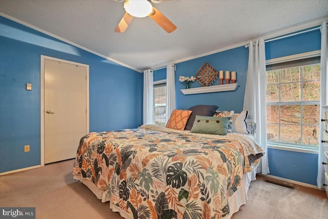 carpeted bedroom featuring multiple windows, a textured ceiling, ceiling fan, and ornamental molding