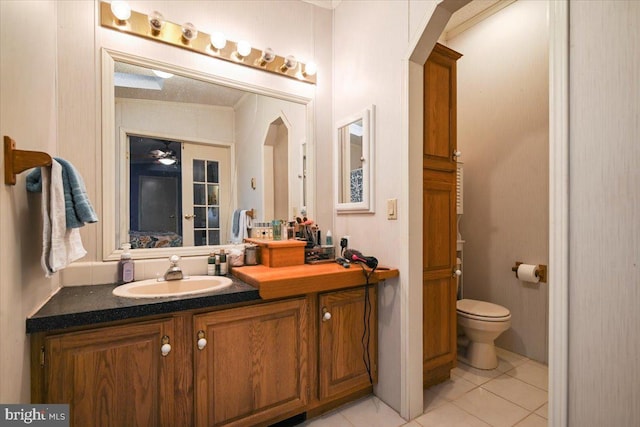 bathroom with tile patterned flooring, toilet, vanity, ceiling fan, and ornamental molding