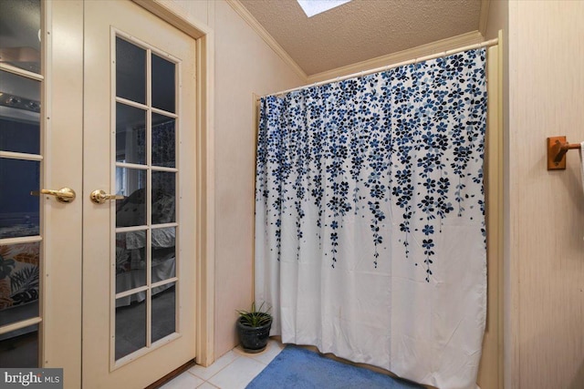 bathroom featuring a skylight, tile patterned floors, ornamental molding, french doors, and a textured ceiling