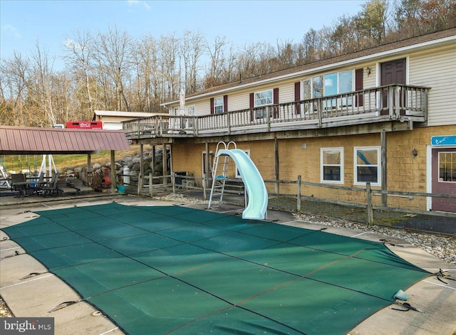 view of swimming pool featuring a water slide, a patio, and a wooden deck