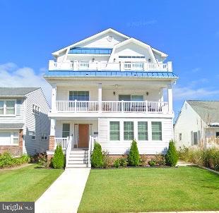 view of front of property featuring a balcony and a front yard