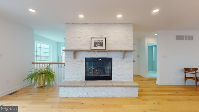 living room with a fireplace and light wood-type flooring