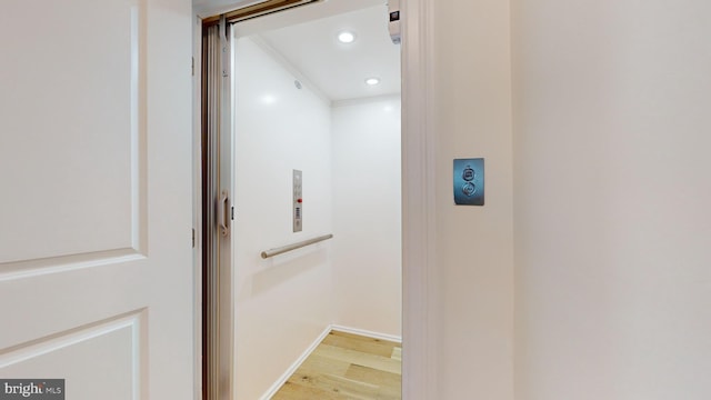 hall with elevator and light wood-type flooring