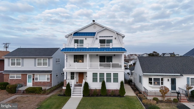 view of front of property featuring a balcony and a front yard