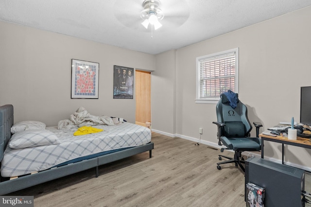 bedroom with a textured ceiling, ceiling fan, and light hardwood / wood-style floors