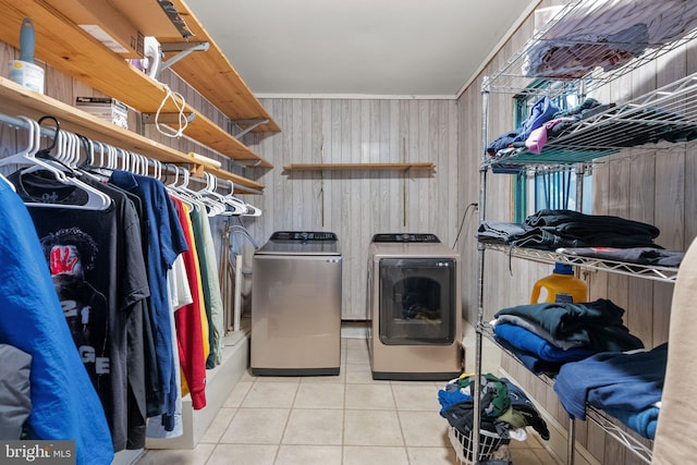 laundry area featuring separate washer and dryer, wooden walls, and light tile patterned floors