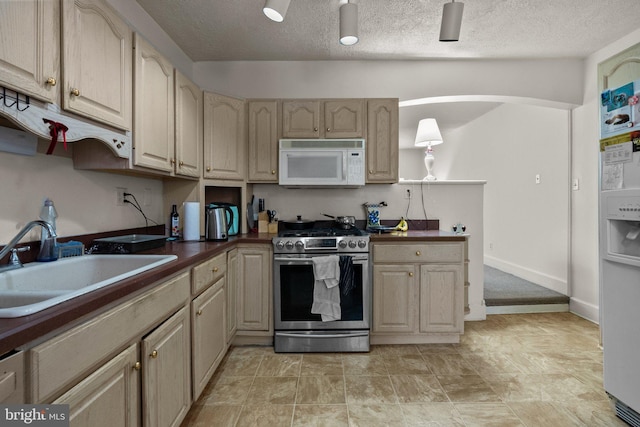 kitchen featuring sink, a textured ceiling, and stainless steel gas range oven