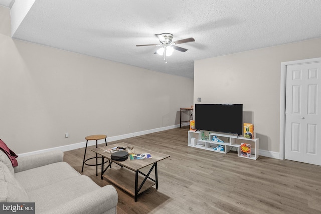 living room featuring ceiling fan, hardwood / wood-style floors, and a textured ceiling