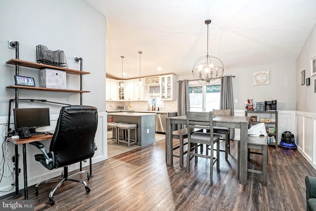 dining space with sink, dark hardwood / wood-style floors, vaulted ceiling, and a chandelier