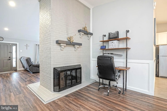 home office with a brick fireplace and dark wood-type flooring