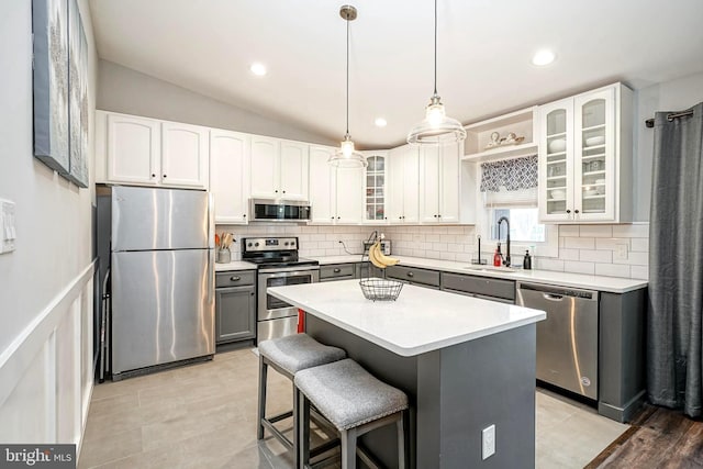 kitchen featuring a kitchen island, lofted ceiling, white cabinetry, appliances with stainless steel finishes, and sink