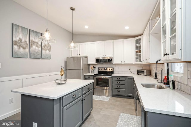 kitchen featuring appliances with stainless steel finishes, gray cabinetry, a center island, white cabinets, and sink