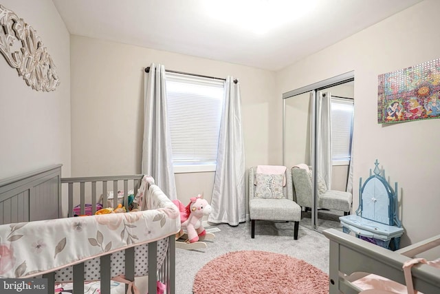 bedroom with a crib, a closet, and light carpet