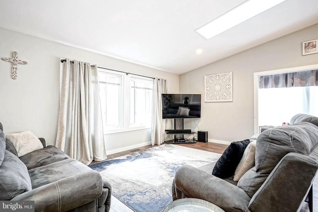 living room featuring hardwood / wood-style flooring and vaulted ceiling with skylight