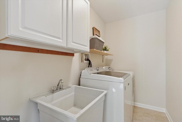 clothes washing area with washing machine and dryer, cabinets, and sink