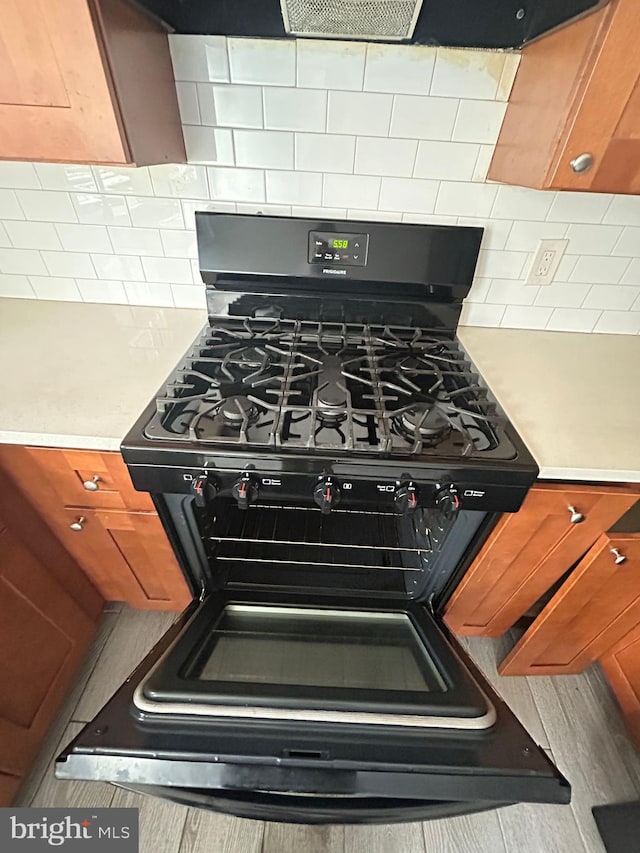 room details featuring black gas range oven and decorative backsplash