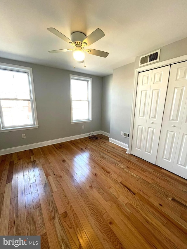 unfurnished bedroom with light hardwood / wood-style floors, a closet, and ceiling fan