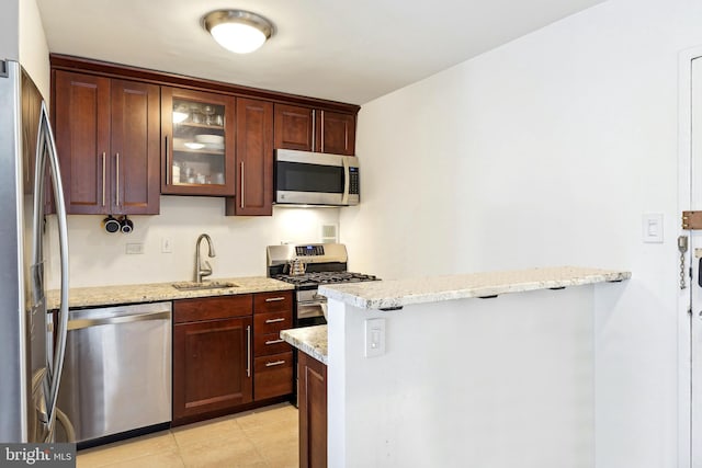 kitchen featuring sink, stainless steel appliances, light stone counters, and light tile patterned floors