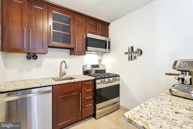 kitchen with light stone counters, stainless steel appliances, light tile patterned floors, and sink