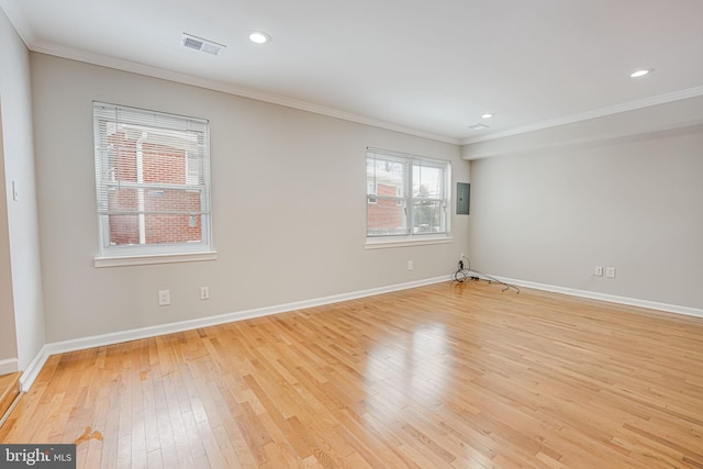 spare room with light wood-type flooring, crown molding, and a healthy amount of sunlight