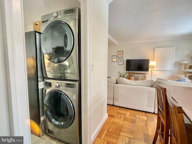 clothes washing area with light parquet floors, crown molding, and stacked washer and dryer