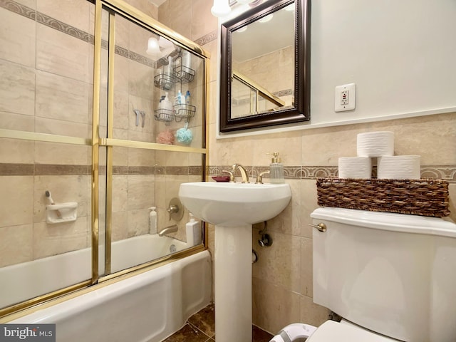 bathroom featuring combined bath / shower with glass door and tile walls