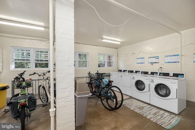 washroom with washer and clothes dryer and brick wall