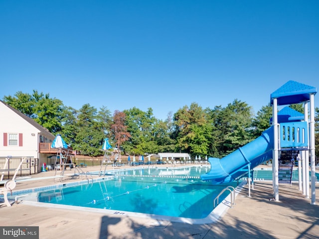 view of swimming pool featuring a playground and a water slide