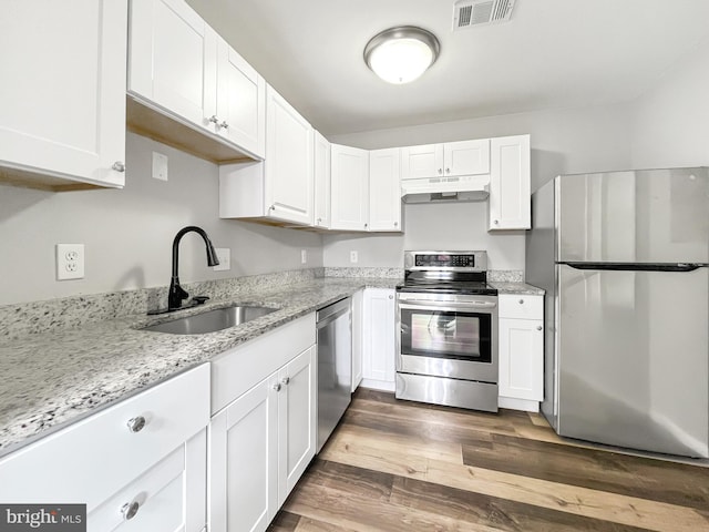 kitchen with white cabinetry, appliances with stainless steel finishes, dark hardwood / wood-style floors, light stone countertops, and sink