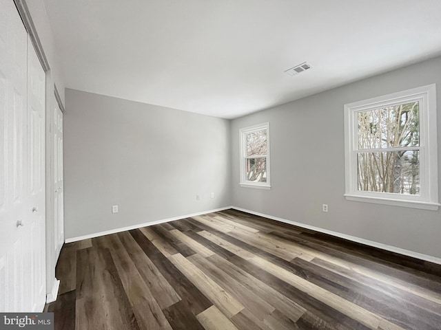 unfurnished bedroom with dark wood-type flooring and a closet