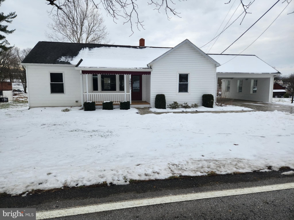 snow covered rear of property with covered porch