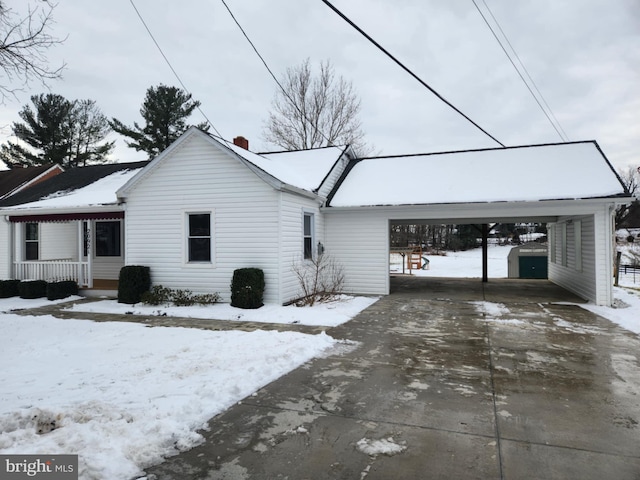 snow covered back of property with covered porch