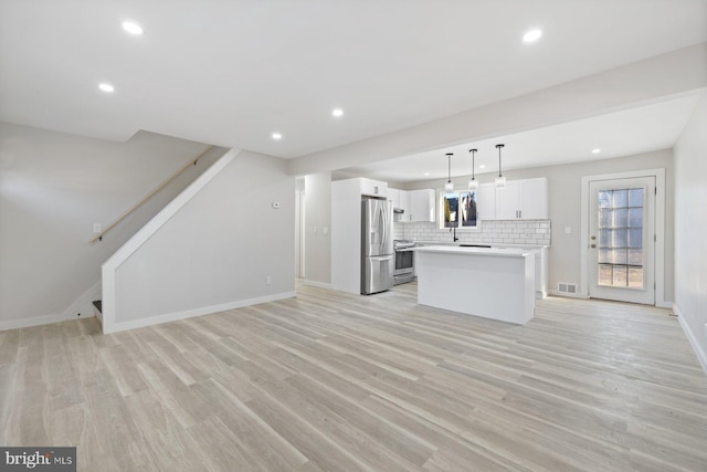 kitchen with stainless steel appliances, a center island, white cabinets, decorative light fixtures, and tasteful backsplash