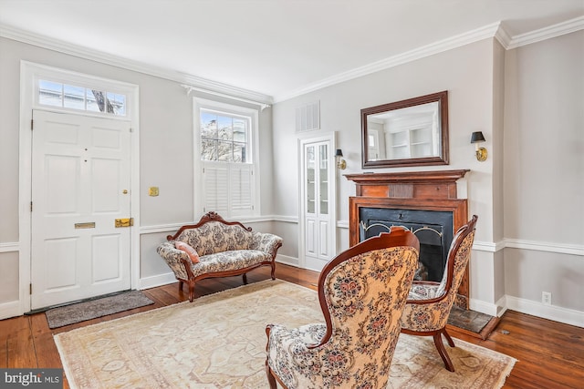 living area with crown molding and hardwood / wood-style flooring