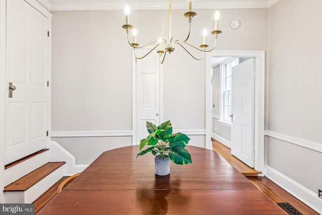 dining room featuring hardwood / wood-style flooring, crown molding, and a chandelier